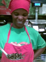 Girl serving a spoonful of cooked caterpillars in the Spar hot foods dept.