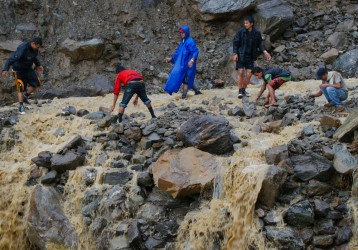 Image: Villagers try to rebuild a flooded road