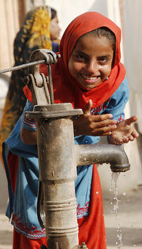 Photo of a girl drinking at a water pump