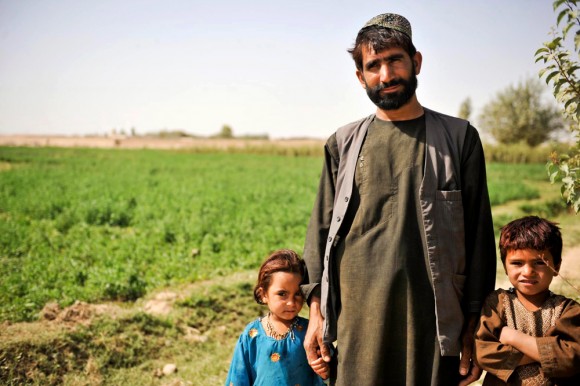 An Afghan farmer stands with his children at a farm in Lashkar Gah