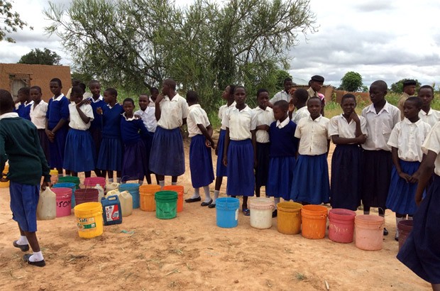 Young girls in uniforms lining up to collect water at Mphangwe’s main water point. Picture: Lindsay Northover/DFID